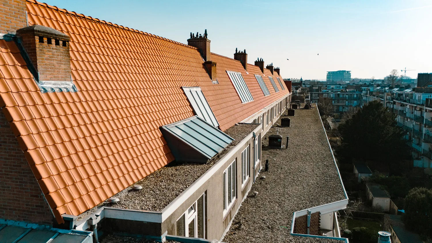 Oranje pannendak met dakkapellen en plat dak aan het Legmeerplein