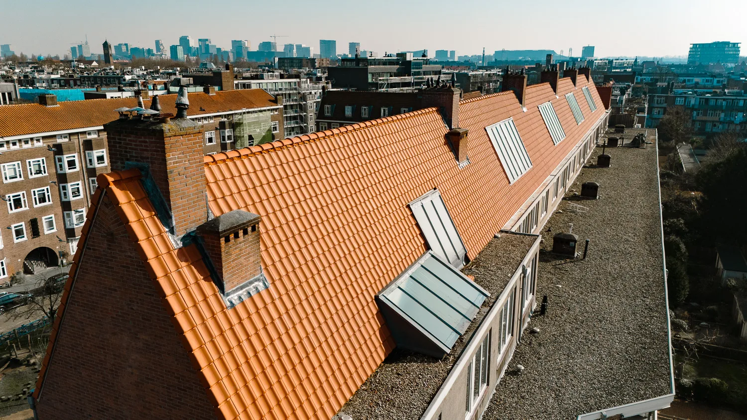 Oranje pannendak met dakkapellen en schoorstenen in Amsterdam
